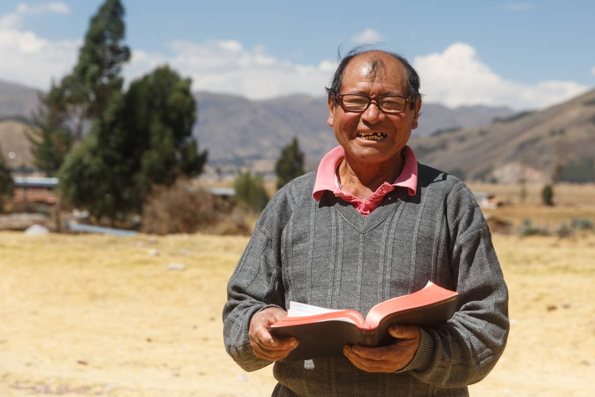 Man from Peru holding a Bible while smiling.